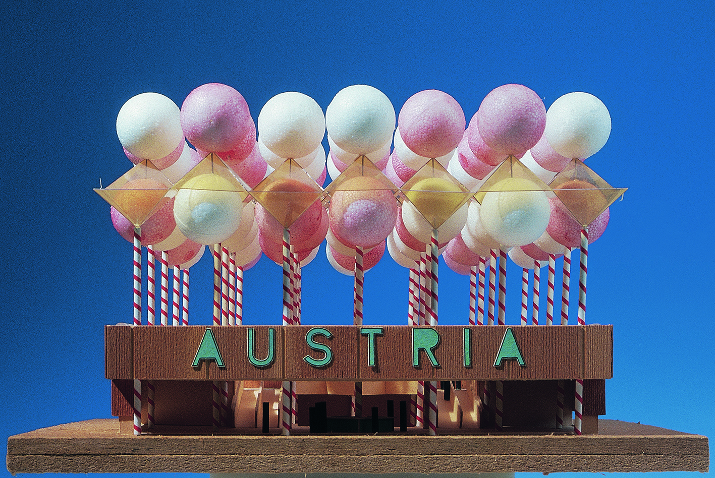 Wooden architcture model of a bungalow with the inscription "Austria" and colorful balls on poles