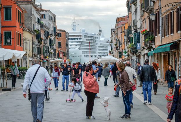 People in a pedestrian zone, behind them you can see a large cruise ship