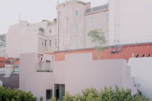 Häuserfassade in sehr hellem rosa mit Bäumen im Vordergrund