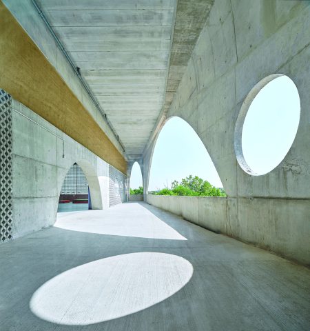 a corridor in a concrete building, (semi)round openings to the left and right of it