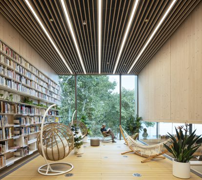 Interior with hammock and hanging chairs, wall of books on the left