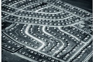 b/w photo from a bird's eye view of a housing estate with many houses of the same size