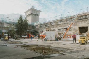 Baustelle mit verschiedenen Fahrzeugen und einem Turm im Hintergrund