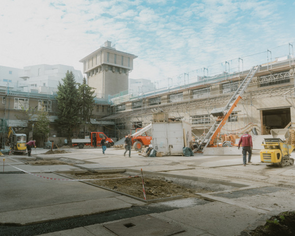 Baustelle mit verschiedenen Fahrzeugen und einem Turm im Hintergrund