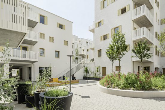 Residential complex with multi-storey houses in light colours with lots of plants in between